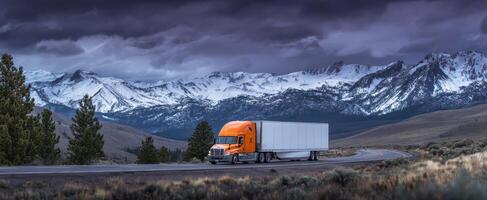 The striking orange truck against a backdrop of majestic snow-capped mountains. photo