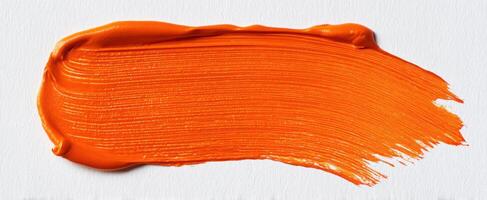 The bright orange paint stroke on a textured canvas backdrop. photo