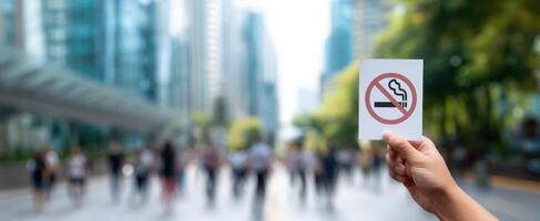 The hand holding a no smoking sign in a bustling urban environment. photo