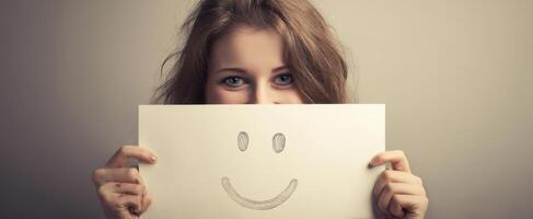 The girl holding a drawn smiley face, radiating joy and creativity. photo