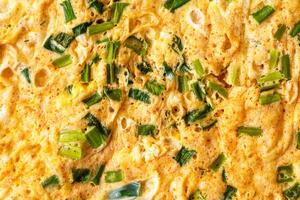 Macro shot capturing the texture of a homemade omelet cooked with fresh green onion slices. Delicious and healthy breakfast concepts. Perfect for food blogs and recipe illustrations. photo