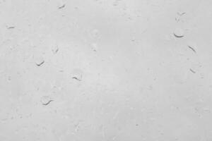Rain drops on a window pane create a natural texture. Transparent liquid element for background or overlay effect concept on a gray surface. photo