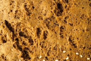 detailed macro view of wholesome whole grain bread texture showing the porous crust of rye country homemade bread, a baking sweet abstract background. photo