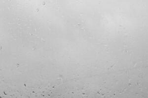 Rain drops on a window create a texture. Transparent liquid element for background or overlay effect concept on a gray surface. photo