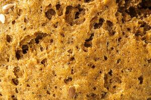 Macro view of wholesome whole grain bread texture showing the porous crust of rye country homemade bread, a baking sweet abstract background. photo