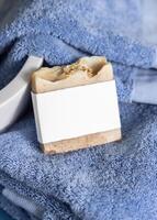 Soap bar with a label on blue towels near vessel sink in bathroom closeup, mockup photo