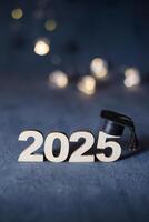 Wooden number 2025 with graduation hat on dark background with bokeh photo