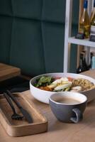 Plate with meat, eggs and avocado and vegetables and cup of coffee on cafe table photo