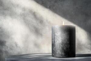 Elegant composition of black textured cylindrical candle in close-up, on minimal matte table and plain gray wall background. ideal for illustrating themes of mindfulness, interior design, meditation photo