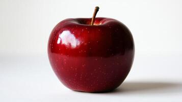 Glossy red apple resting on white surface, casting soft reflections and revealing smooth contours, symbolizing fresh, vibrant nutrition photo