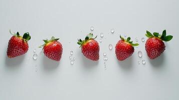 Six fresh, ripe strawberries with water droplets are neatly arranged on a clean white background, creating a vibrant and appetizing display photo
