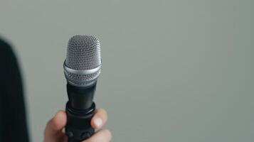 Influencer marketing and brand ambassadors concept. Microphone held in hand against a simple background. photo