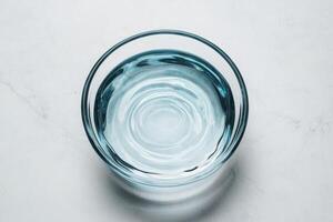Clear glass bowl filled with water on a light background. Pure water unpolluted concept. photo