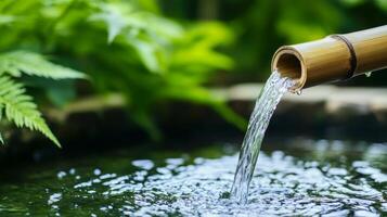 Bamboo water fountain with lush greenery background. Crystal water with eco-friendly concept. photo