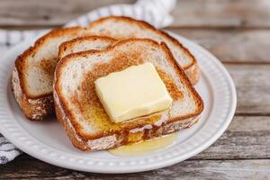Golden butter melting on toasted bread slices on a plate. photo