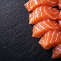 Fresh salmon slices on a textured dark surface. photo