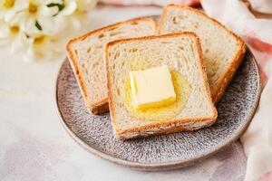 Three slices of bread with butter on a plate, styled elegantly. photo