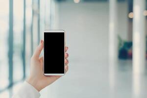 Hand holding a smartphone in a bright, modern setting. photo