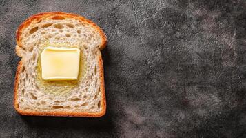 Slice of bread with a pat of butter on a dark background. photo