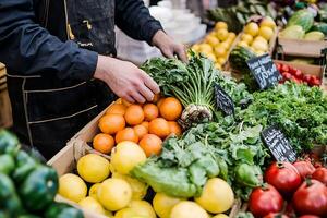 market vendor arranging vegetables and fruits on display photo