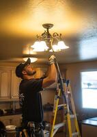 electrician installing ceiling light using tools and ladder photo