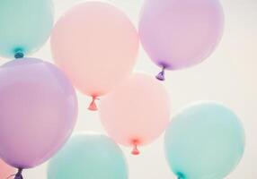 A group of colorful balloons gently float in the bright, expansive sky. photo