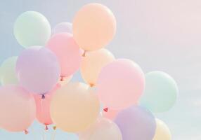 A cluster of colorful pastel balloons floating gracefully in the bright, open sky. photo