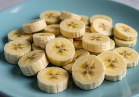 Close up shot of fresh banana slices on a vibrant blue plate, perfect for healthy eating. photo