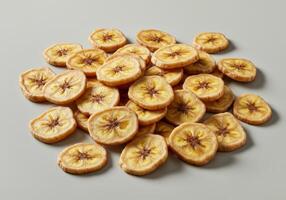A collection of appetizing banana chips are presented on a simple light gray backdrop. photo