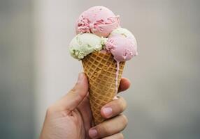 Hand holds a delicious ice cream cone with multiple scoops on a blurred background. photo
