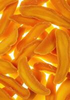 A bright, close up view of several overlapping dried mango slices, ready to eat. photo