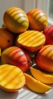 A vibrant display of ripe mangoes, some sliced open, with natural light and shadows. photo