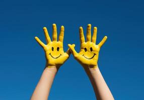 Bright and joyful image featuring hands painted with happy faces under a clear sky. photo