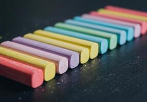 A collection of colorful chalk pieces, arranged in a neat, diagonal line on a dark background. photo