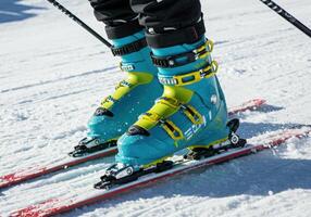 Close-up shot of bright blue and yellow ski boots and skis on a snow-covered slope. photo