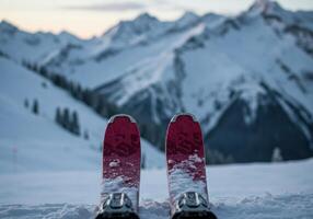 A scenic view of skis in the snow, with mountains in the background during dusk photo