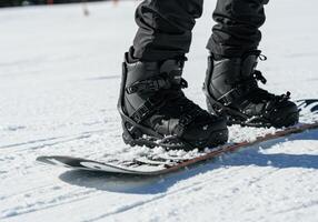 A close up view of snowboard boots attached to a snowboard on a fresh snowy surface. photo