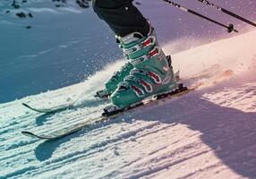 A skier in action glides down a snow covered slope on a beautiful sunny day. photo