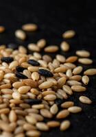 A macro shot showing a mix of sesame seeds, showcasing their different colors and textures. photo