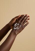 A close-up shot of hands applying cream on a beige background, promoting beauty. photo