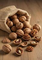 Walnuts spill from a burlap sack on a wooden surface, showcasing nuts. photo