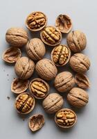 An assortment of walnuts, some whole and some shelled, presented on a grey surface. photo