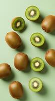 A vibrant display of fresh kiwi fruit, both whole and sliced, against a pale green backdrop. photo