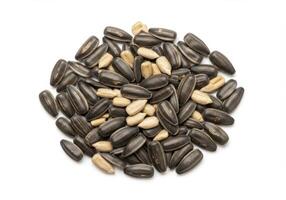 A circular arrangement of sunflower seeds, both with and without their shells, against a white backdrop. photo