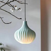 Elegant ceramic pendant lamp hanging indoors with light illuminating its fluted design casting a soft glow, complemented by a delicate branch with white blossoms adding artistic flair photo