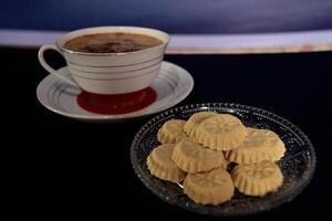 High angle view of a cup of coffee and a bunch of kue satu or kue koya, a popular dry traditional cookie commonly found in Java, made of sweet mung bean powder that crumbles when bitten. photo