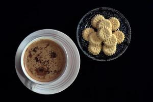 Flat lay view of a cup of coffee and a bunch of kue satu or kue koya, a popular dry traditional cookie commonly found in Java, made of sweet mung bean powder that crumbles when bitten. photo