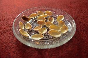 Close up of Pistachio nut shells or Pistacia vera on a clear saurcer, a cashew-related seed that can be eaten fresh or roasted and is commonly used in a variety of desserts. photo