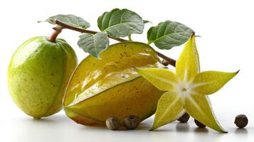 Closeup of Ripe Yellow Starfruit with Green Leaves and Black Peppercorns on White Background photo