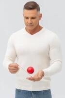 Focused Man Playing with Red Yo Yo Against Gray Background photo